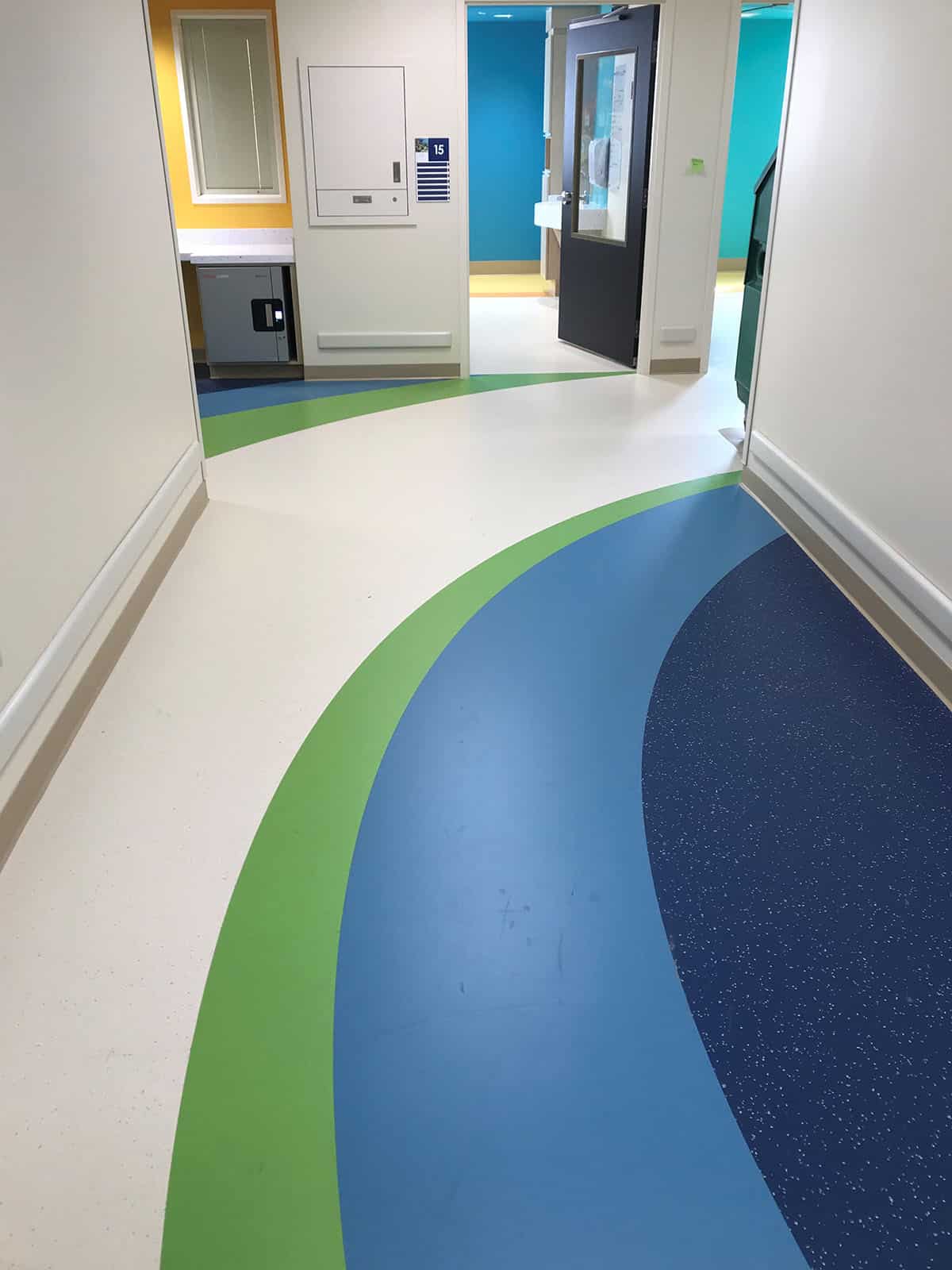 Hospital hallway flooring of blue, green and white tiles and a blue door
