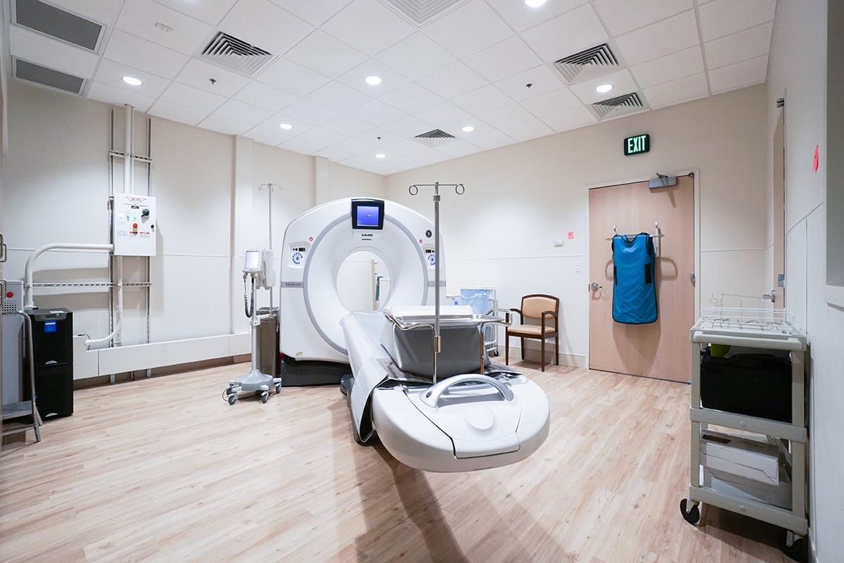 Different view of laminate flooring of the CT scanner room at Bethesda Health City with a an exit sign on the wall.