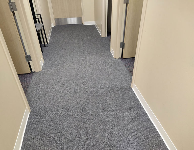 view of office hallway with gray commercial carpet